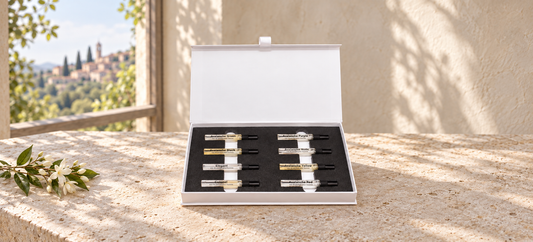 Discovery Set II with eight perfume miniatures on limestone beside jasmine in soft window light